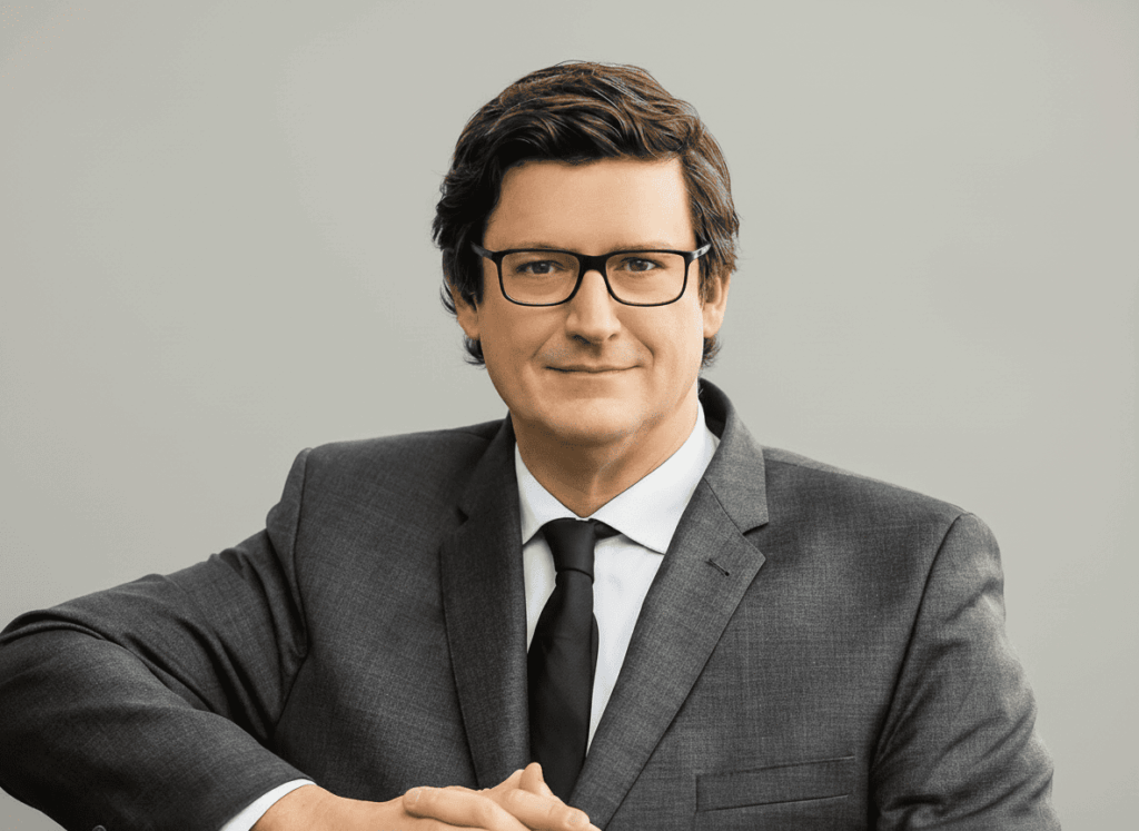 Portrait de Arnaud Etienne, Groupe ENSIO, costume gris et cravate noire sur fond gris clair