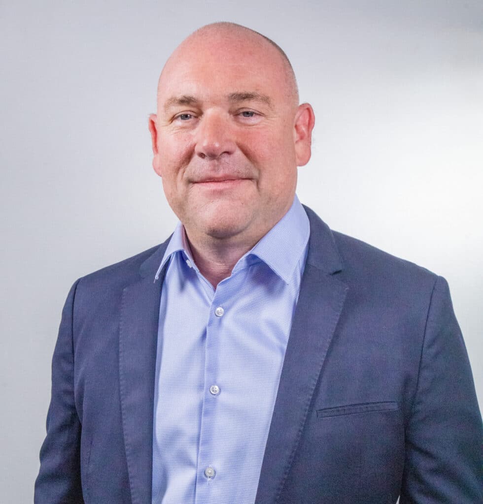 Portrait de Stéphane Seguin, Directeur Général France Est & Nord ENSIO Group, veste bleu marine et chemise bleue claire sur fond gris clair